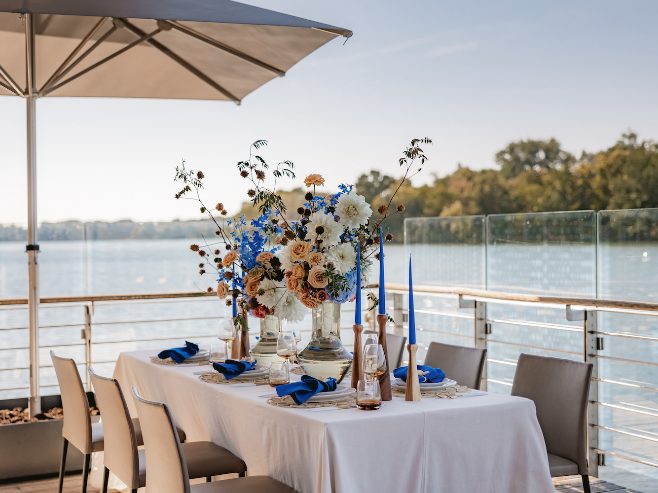A beautifully laid table with lush, colourful floral decorations amidst autumnal table decorations emphasises the natural beauty of autumn with a focus on shades of blue and caramel.