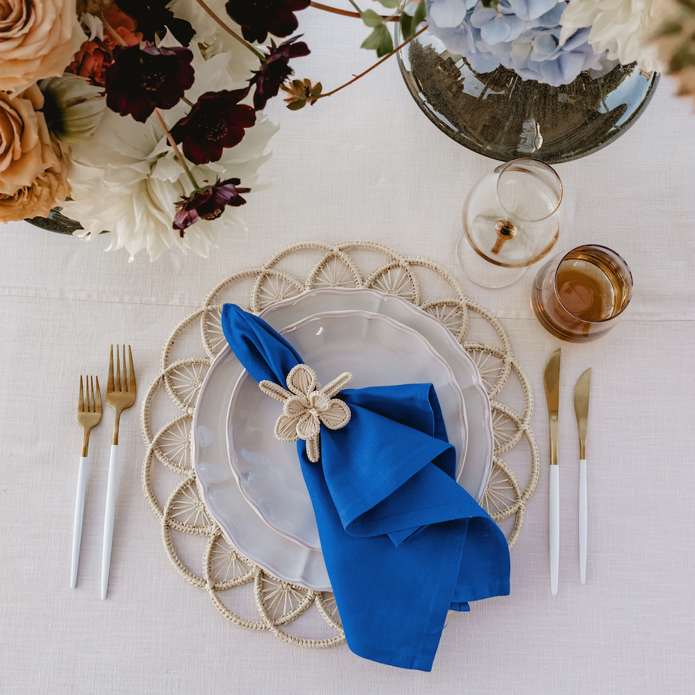 Close-up of an elegantly laid table from above, presenting autumnal table decorations in shades of blue and caramel, including crockery, cutlery and decorative elements, perfect for the autumn season.