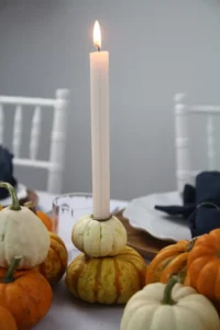 Weiße und orange Kürbisse auf einem herbstlichen Tisch mit Kerze