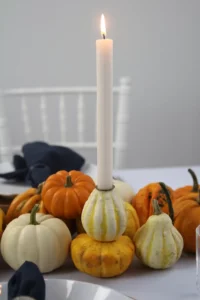 Weiße und orange Kürbisse auf einem herbstlichen Tisch mit Kerze