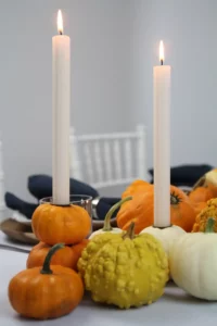 Weiße und orange Kürbisse auf einem herbstlichen Tisch mit Kerzen
