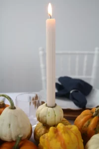 Weiße Zierkürbisse auf einem rustikalen Tisch als DIY Kerzenständer.