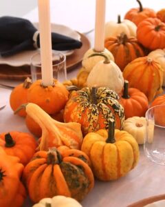 Weiße und orange Kürbisse als herbstliche Tischdekoration