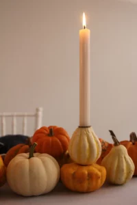Weiße und orange Kürbisse auf einem herbstlichen Tisch mit Kerze