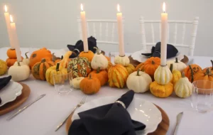 Herbsttisch mit Kürbissen, Kerzen und Akazienholzplatztellern mit eisblauer Leinentischdecke.
