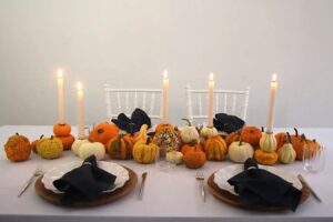 Weiße und orange Kürbisse auf einem herbstlichen Tisch mit brennenden Kerzen