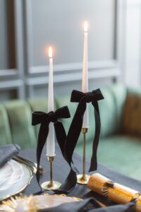 Goldene Kerzenständer mit weißen Kerzen und Samtschleifen auf einer eleganten Silvester-Tafel.