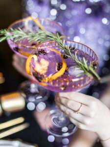 Eine junge Frau hält einen Cocktail in einer Charleston-Sektschale mit feinem Goldrand.
