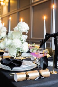 Hochformat-Aufnahme einer elegant dekorierten Silvester-Tafel in Schwarz und Gold.