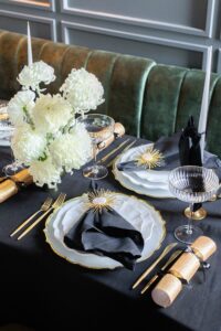 Silvester-Tischdeko mit Gold, Schwarz und Weiß im Hochformat, inklusive floraler Highlights.