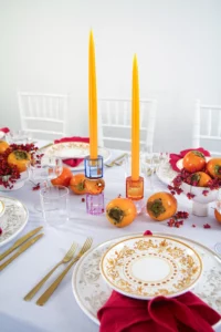 Yellow taper candles in crystal candle holders from EJA, embedded in a table decoration with fruit.