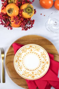Hand-painted plate on a wooden platter with persimmon and berry decoration.
