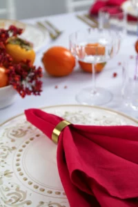 Hand-painted plate with red napkin, surrounded by persimmons and berries.