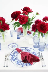 Detailed view of a plate with blue decoration, red napkin and light-coloured cutlery handles on a white tablecloth.