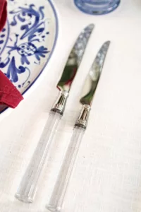 Two knives from the Doric Clear cutlery set with transparent handle on a white linen tablecloth.