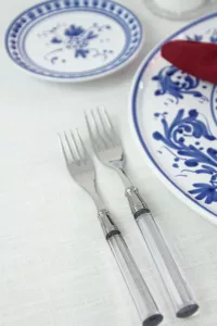 Doric Clear cutlery set with transparent acrylic handle on white linen tablecloth.