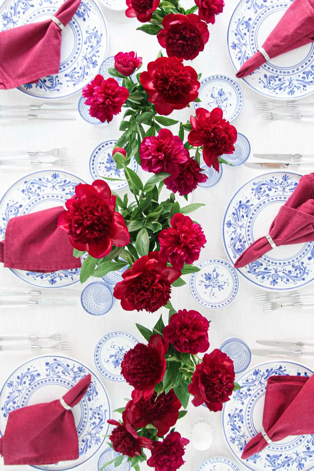 magnolias-on-silk-table-of-the-month-mai-peony-red-blue-table-inspiration-341 View from above of an elegant spring table with red peonies, blue and white crockery and ruby-red linen napkins.