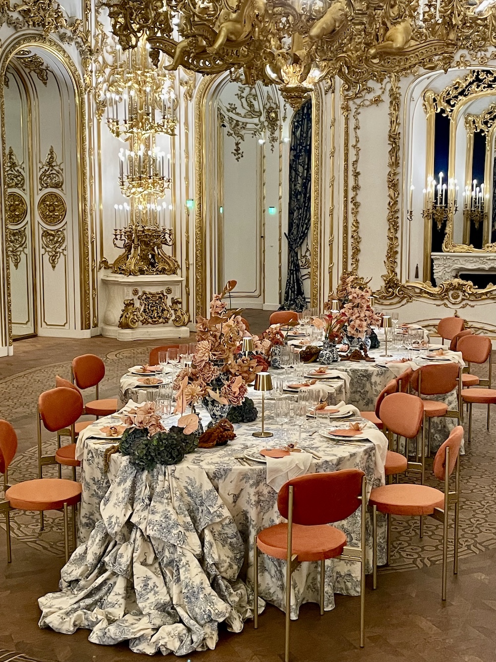 „Opulently laid table in Palais Liechtenstein Vienna with floral arrangements, baroque stucco and gold decorations and draped fabric tablecloths in the neo-baroque style.