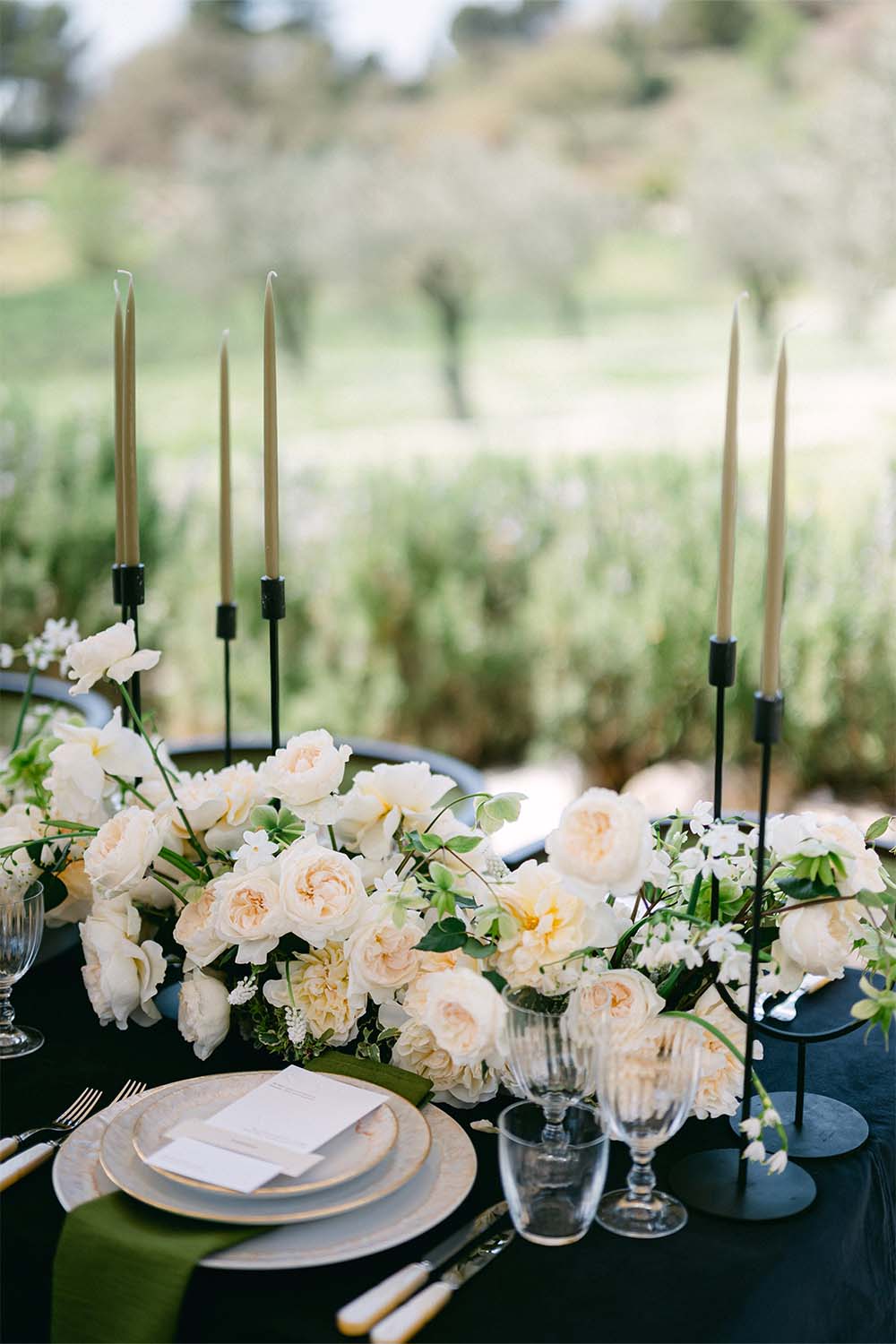 Table decoration with cream-coloured roses and tall black candle holders