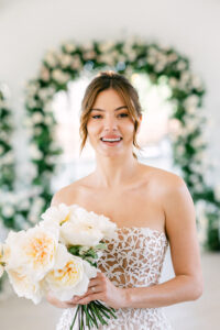 Bride in a floral setting with a cream-coloured bouquet of roses at the Reference Masterclass