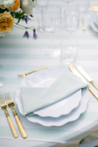 Close-up of an aquamarine-coloured table setting with white crockery and gold cutlery