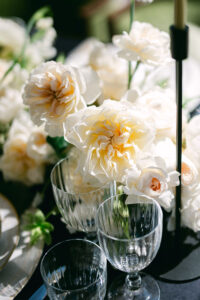 Cream-coloured garden roses and glassware in the sunlight on an elegant table