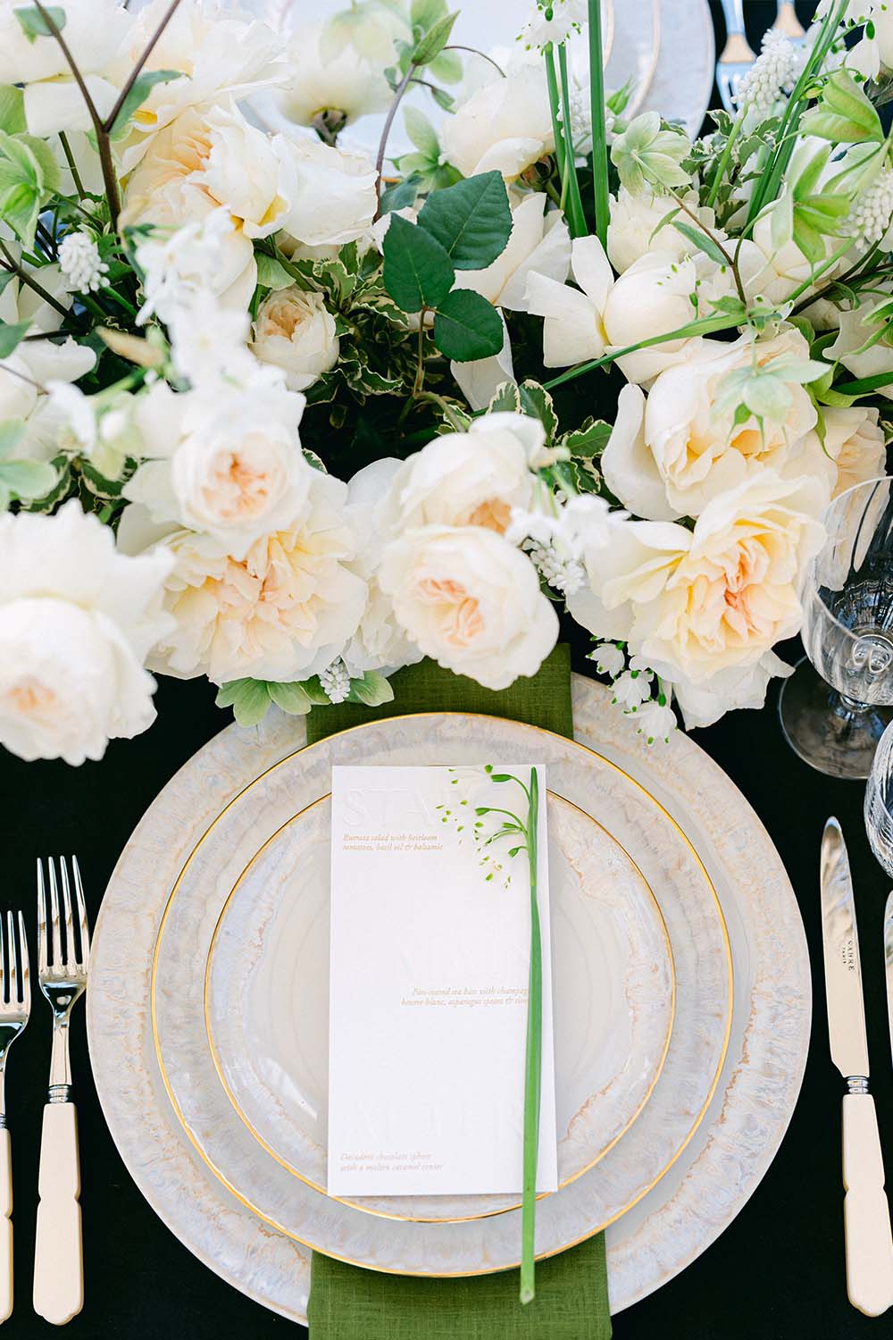 Elegant place setting with light-coloured plates, menu card and floral arrangements from the La Mer du Soir collection.